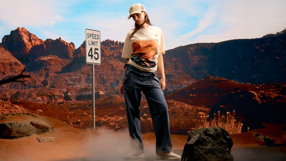 fashion model posing in a desert landscape with a speed limit sign in the background