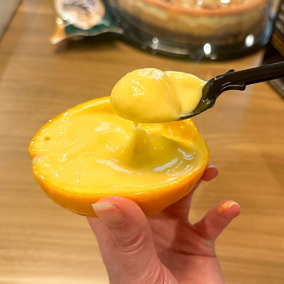 scoop of creamy mango dessert held in a half orange peel