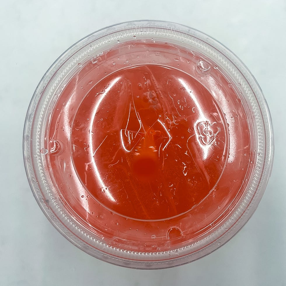 transparent cup containing a pink beverage with condensation on the surface