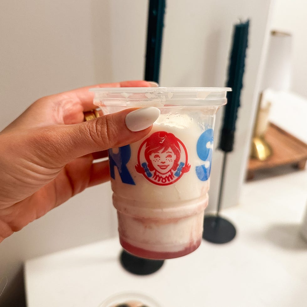a hand holding a frosty dessert cup with red and blue branding