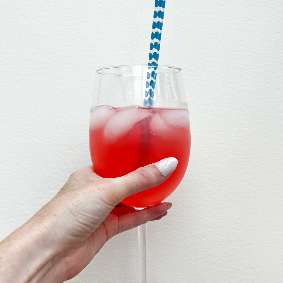 hand holding a wine glass with a cocktail and straw
