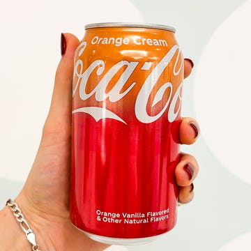 a hand holding a cocacola can with an orange cream flavor a hand holding a cocacola can with an orange cream flavor