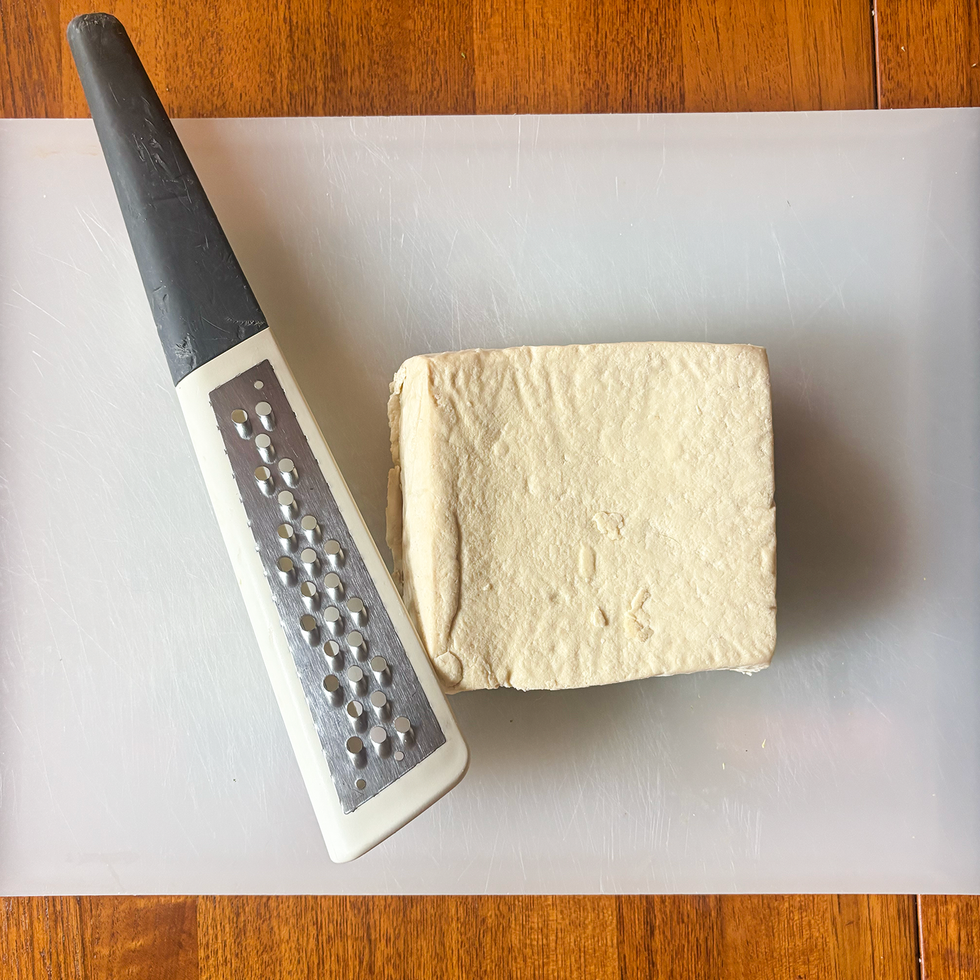 tofu block and grater on a cutting board