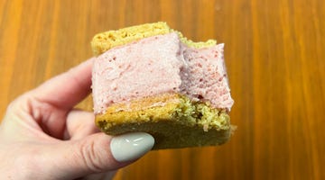 hand holding strawberry ice cream sandwich with bite taken out of it