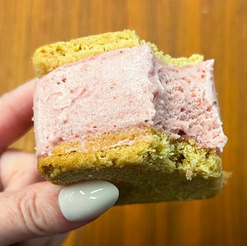 hand holding strawberry ice cream sandwich with bite taken out of it hand holding strawberry ice cream sandwich with bite taken out of it