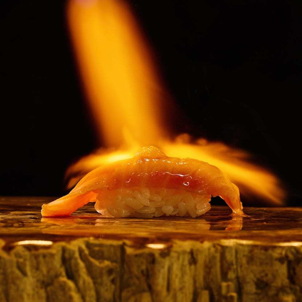 piece of sushi being torched with fire close up