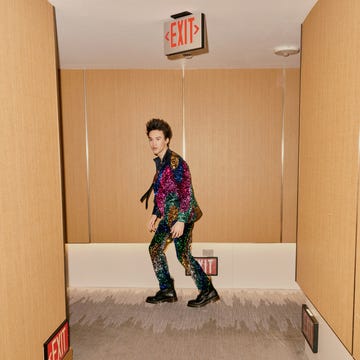 individual wearing a colorful sequined outfit walking in a hallway with exit signs individual wearing a colorful sequined outfit walking in a hallway with exit signs