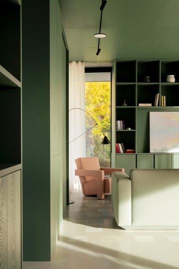 modern green living room with angular pale pink armchair in corner