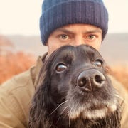 This is an image selfie of james middleton outside wearing a blue beanie and a black dog sitting in front of his face