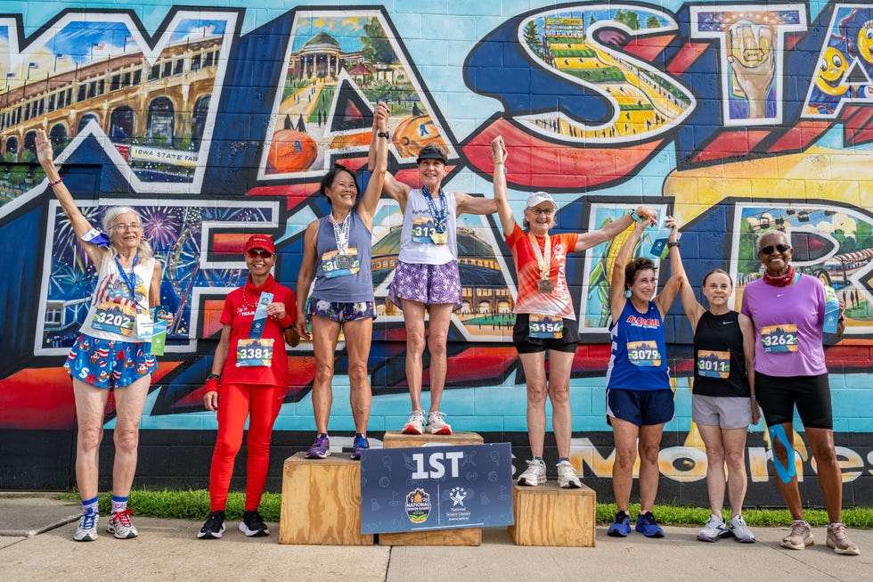runners standing on a podium in front of a mural