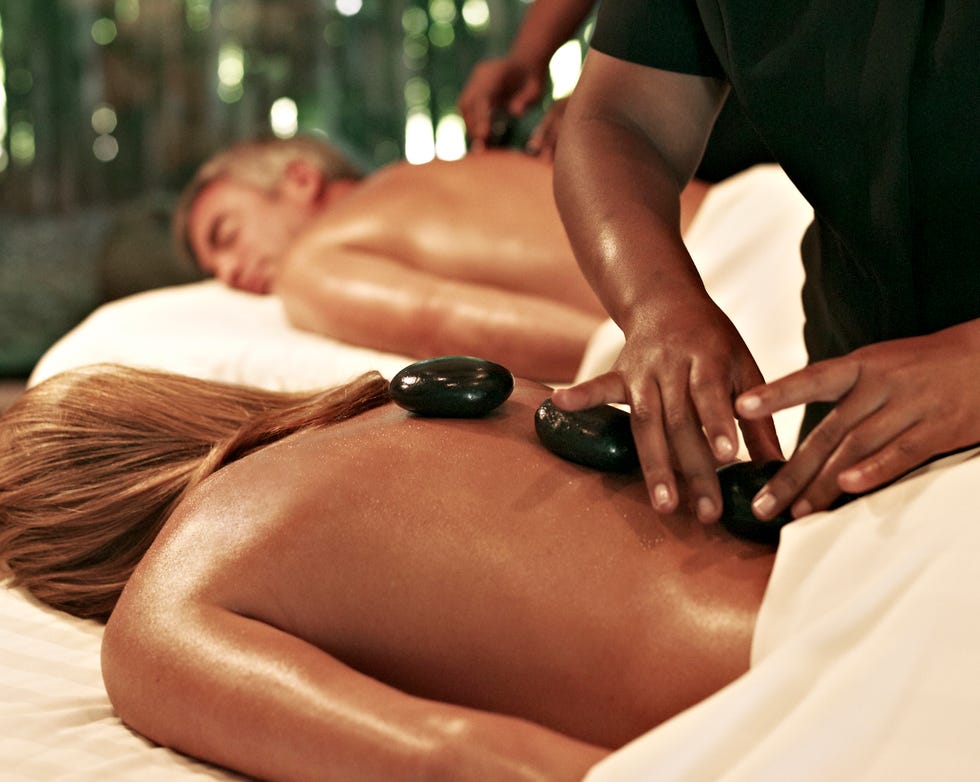 hot stone massage session with a therapist applying heated stones to a clients back