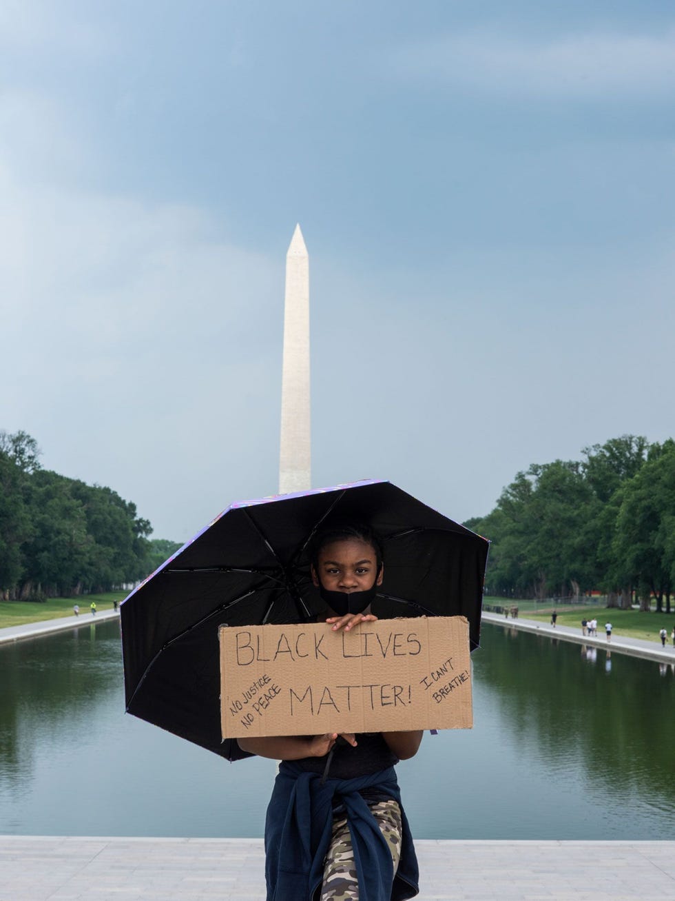 Bij de Reflecting Pool voor het Washington Monument op de achtergrond beschermt Jayla Harris zich met een paraplu tegen de zon Ik hoop dat er verandering komt in de werkwijze van de politie zegt zij over de reden van haar komst naar de demonstratie in de hoofdstad