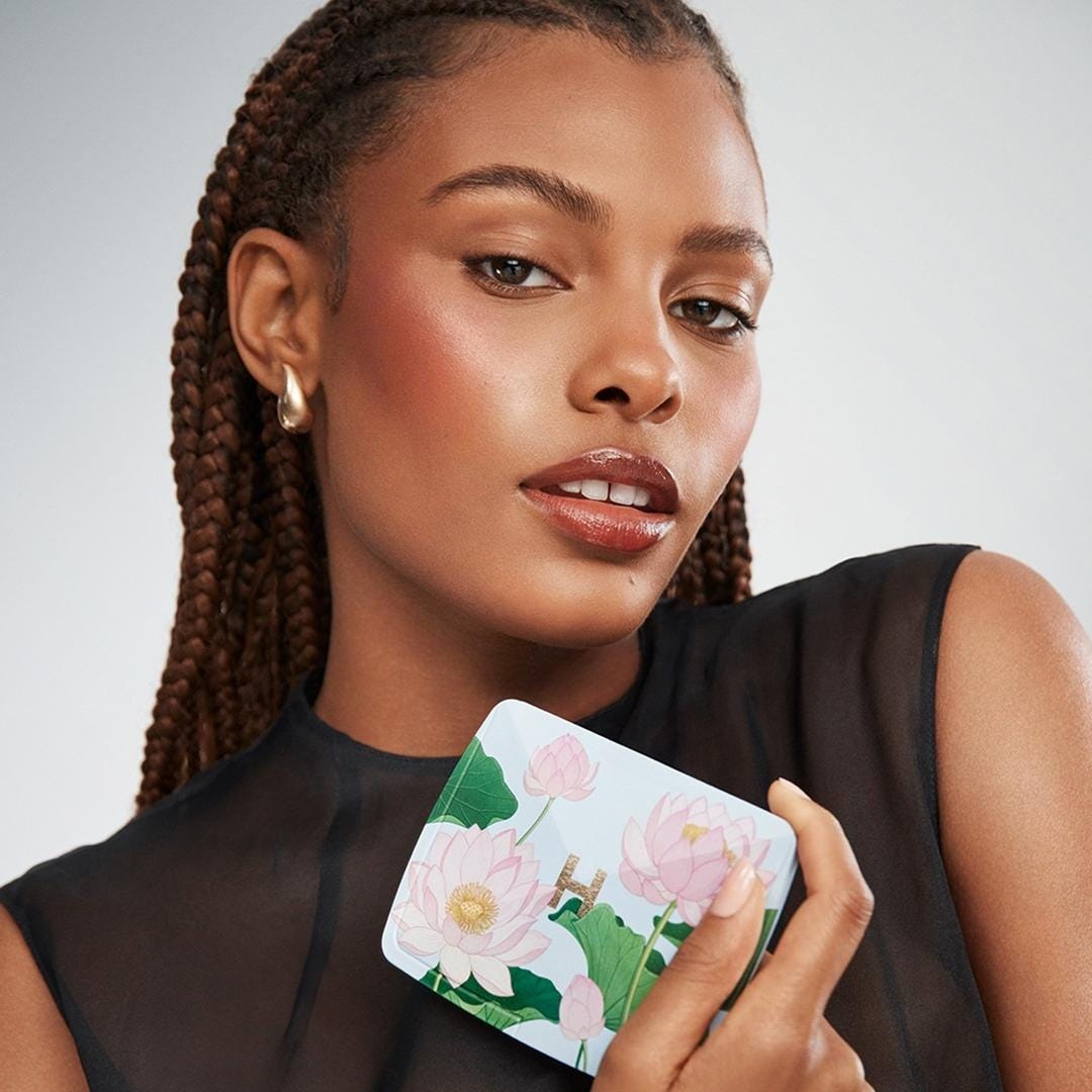 person holding a decorative compact case with floral design