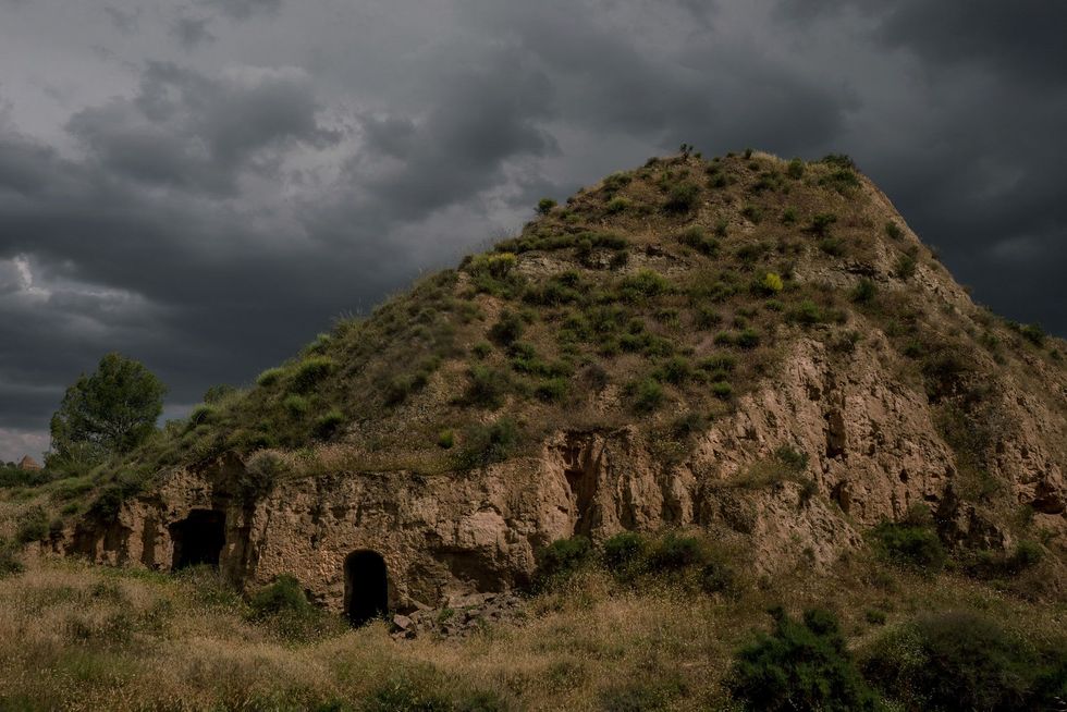 De lucht betrekt boven de ingang van een grotwoning in Benala een dorpje in de bergen van ZuidSpanje