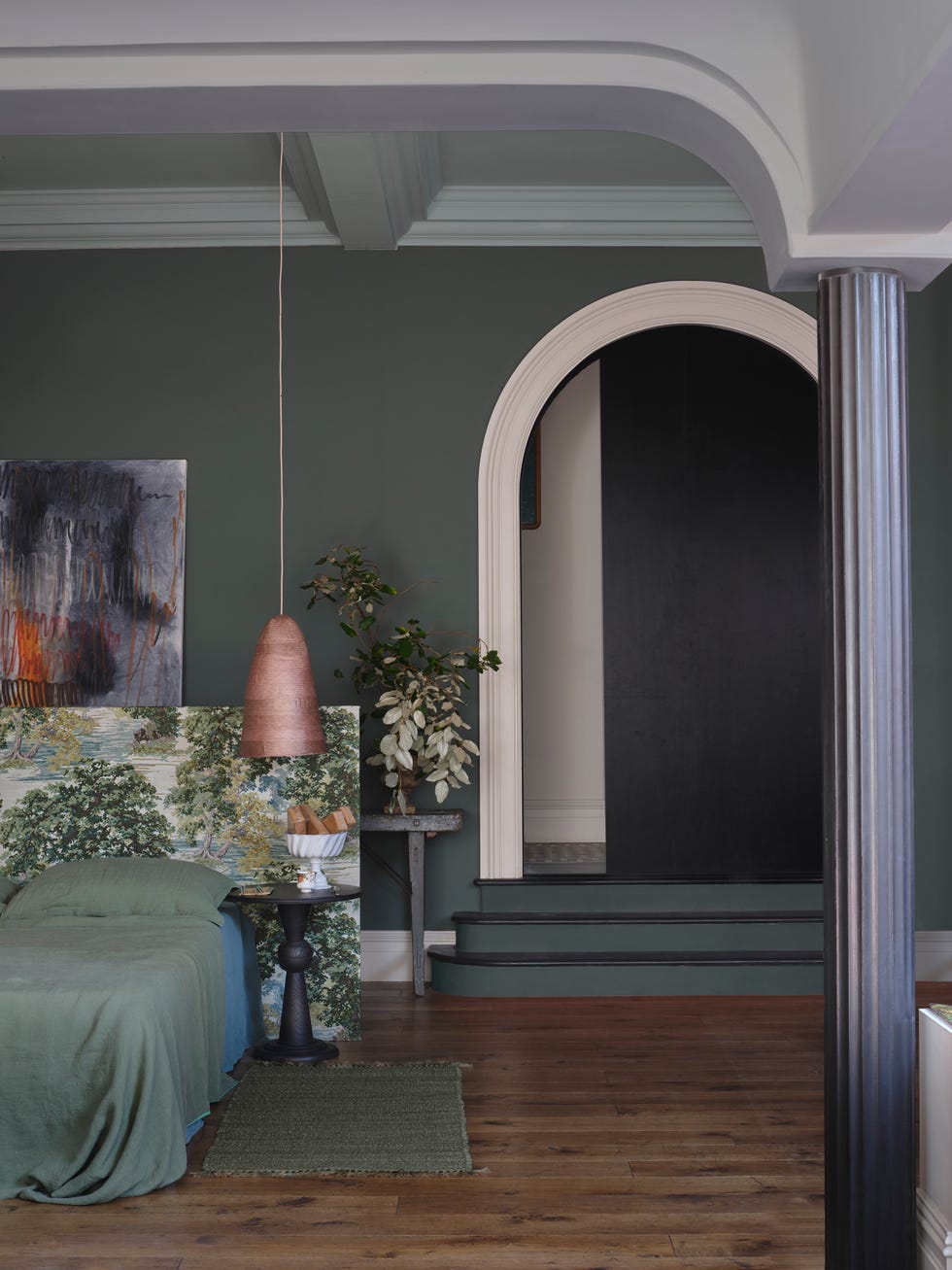 stylish bedroom with a modern aesthetic featuring greenery a painted wall and an archway