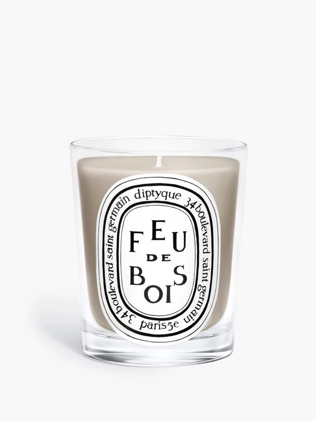 Scented candle in a clear glass container with an artistic label.