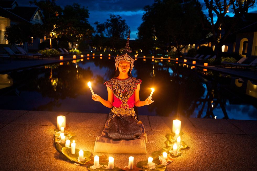 Kaarsen omringen een jonge Nang Keodanser in Luang Prabang de voormalige keizerlijke hoofdstad van Laos die nu bereikbaar is met eenbullet train