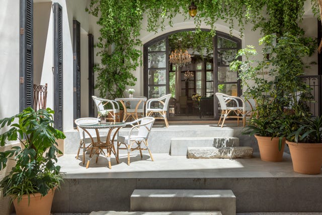 Outdoor seating area featuring bistro tables and chairs surrounded by greenery.