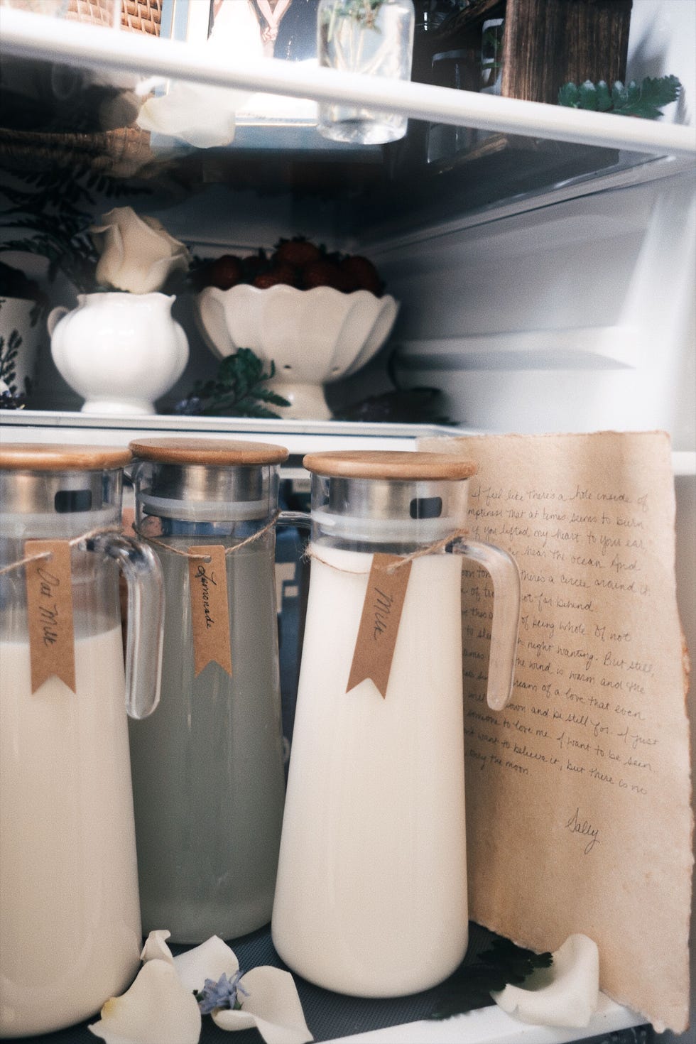 Refrigerator setup with handwritten letter and milk jugs with homemade labels in cursive