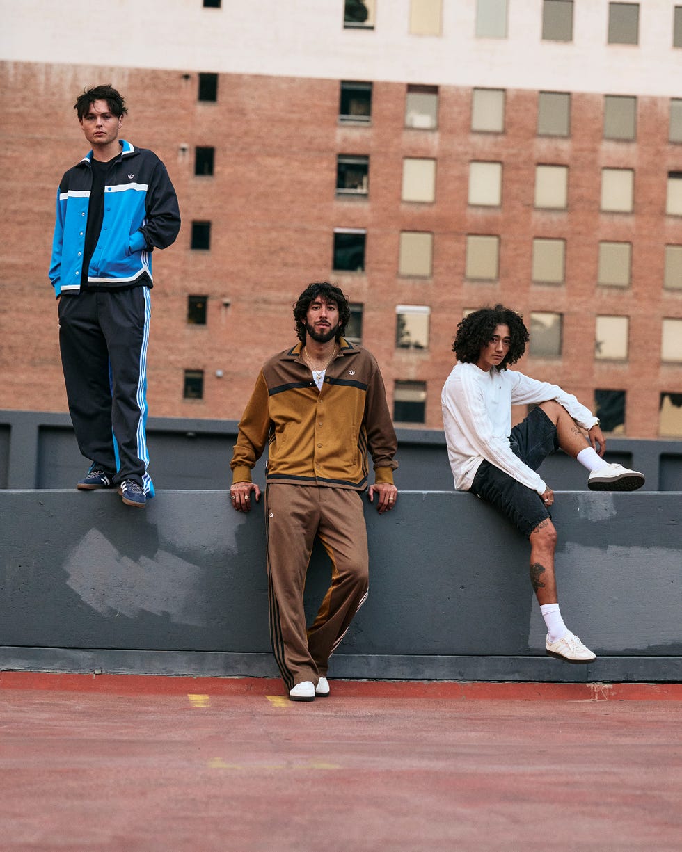 three individuals dressed in sporty outfits pose on a ledge