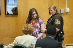 a police officer holding onto the arm of slender man stabbing suspect anissa weier during a courtroom appearance