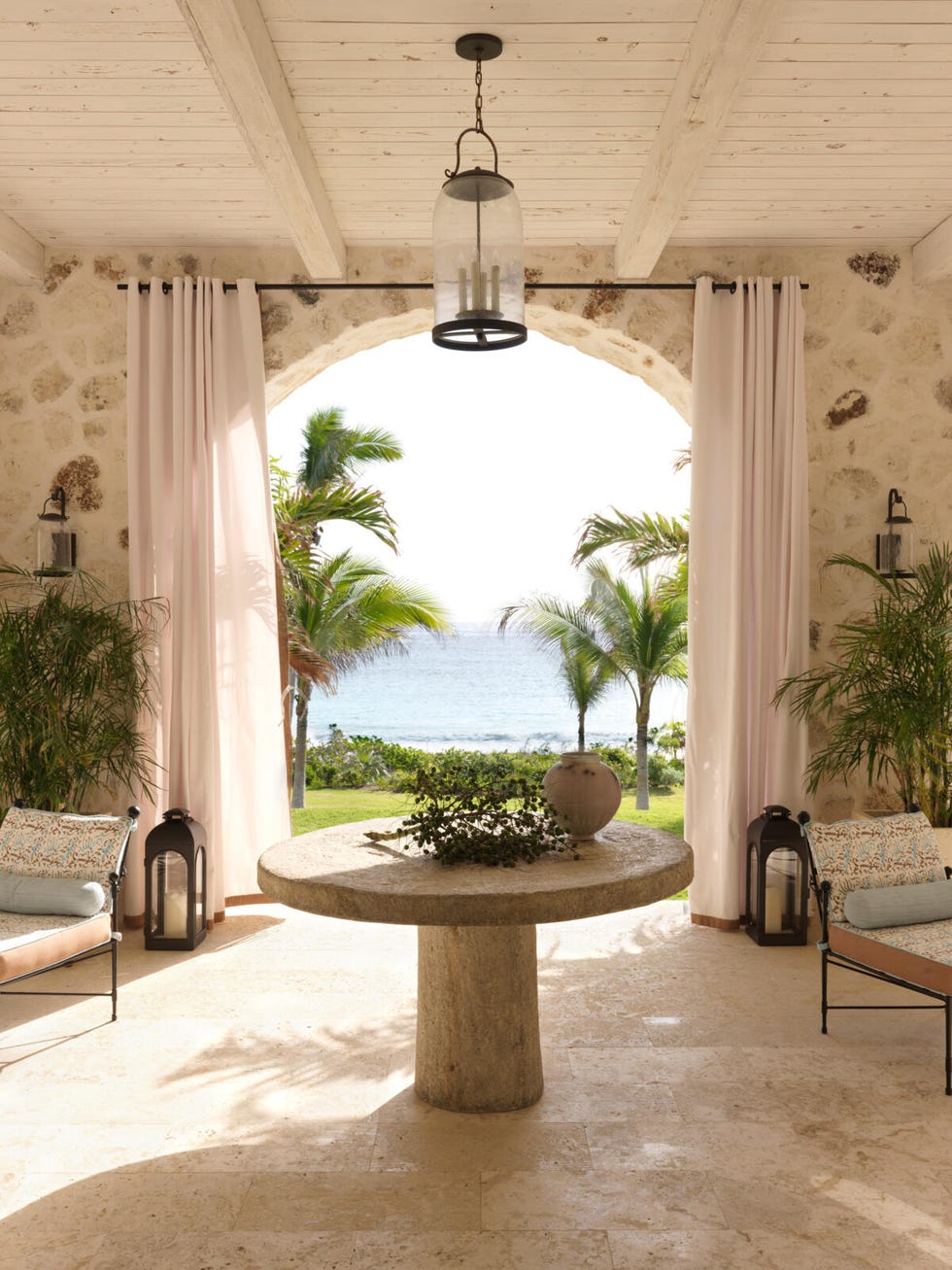 Photograph of a loggia by the sea with a table and two benches.