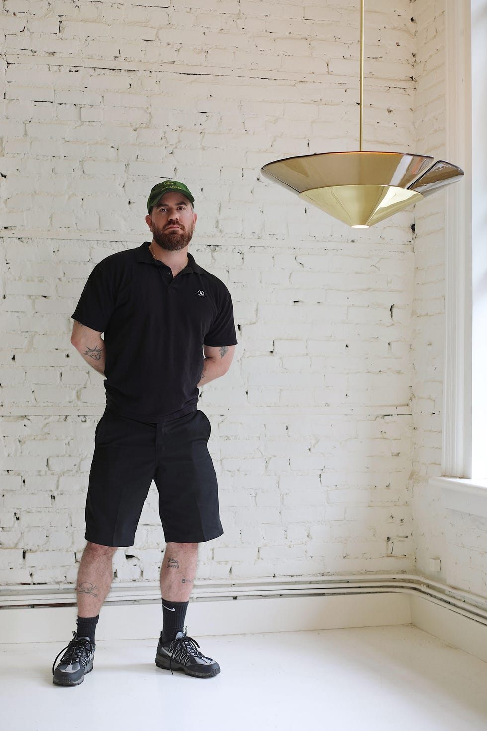 A person stands in a minimalist room with a hanging lamp.