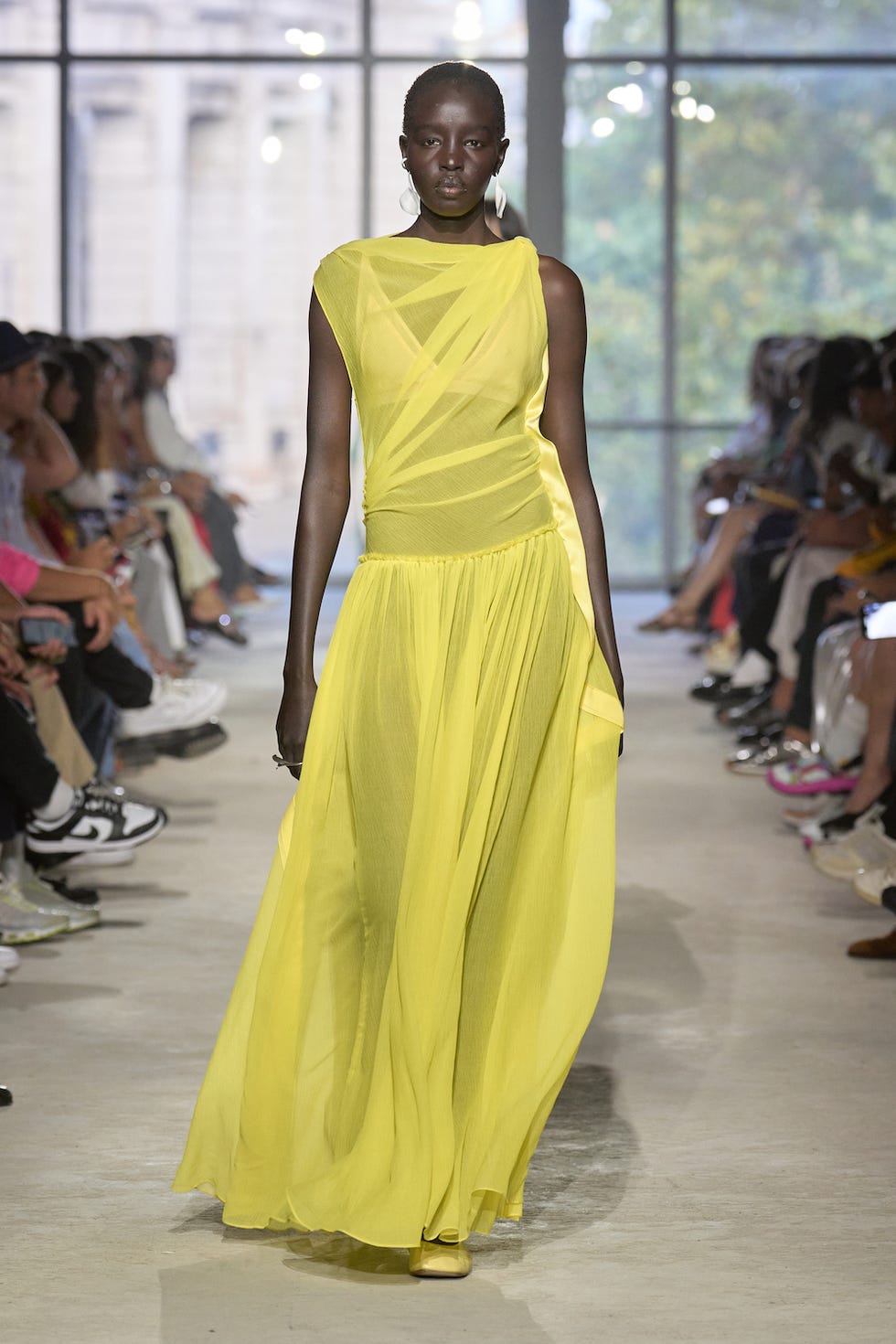 a model wears a sheer, asymmetrical citron dress on the spring 2024 runway for phillip lim