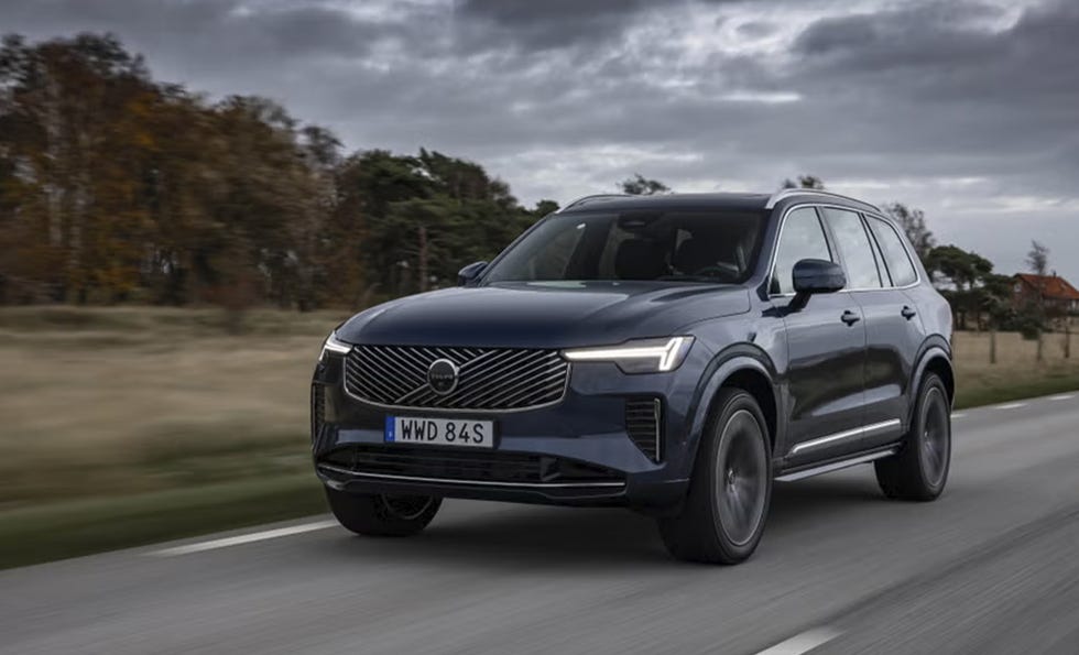a modern suv in motion on a road with trees in the background