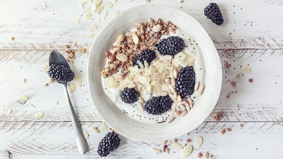 Breakfast bowl with homemade granola, dried fruits, blackberries and almond yogurt