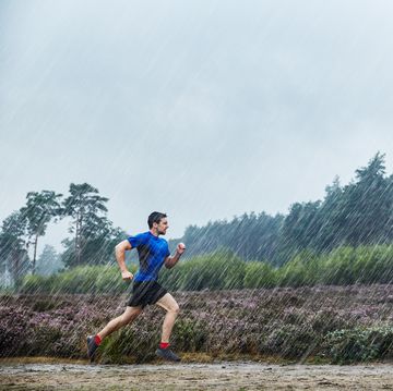 een man loopt hard in de regen