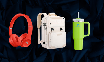 headphones backpack and stanley cup on dark blue silk background