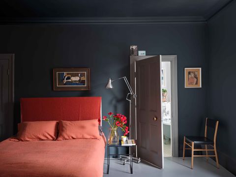 a bedroom with a red bed and dark gray walls