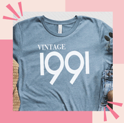This is an image 1991 tshirt, wine bag, bloomscape aloe plant, customizable welcome mat, brown girl jane candle
