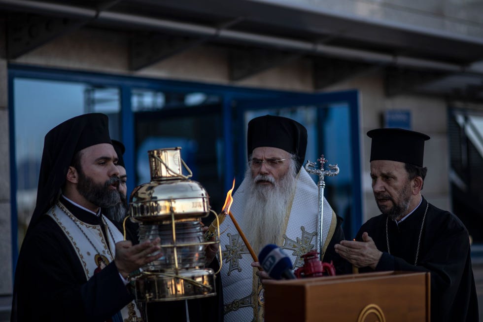 Op de luchthaven van Athene draagt de Archimandriet Damianos de lantaarn met daarin het Heilig Vuur dat enkele uren eerder op Heilige Zaterdag vanuit Jeruzalem naar Griekenland is overgevlogen