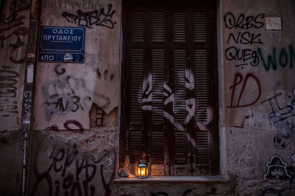 Het Heilig Vuur gloeit in een eenzame lantaarn naast de gesloten deur van de kerk Metohi Panagiou Tafou in Athene waar de aankomst van het Heilig Vuur normaliter door grote aantallen gelovigen wordt gevierd