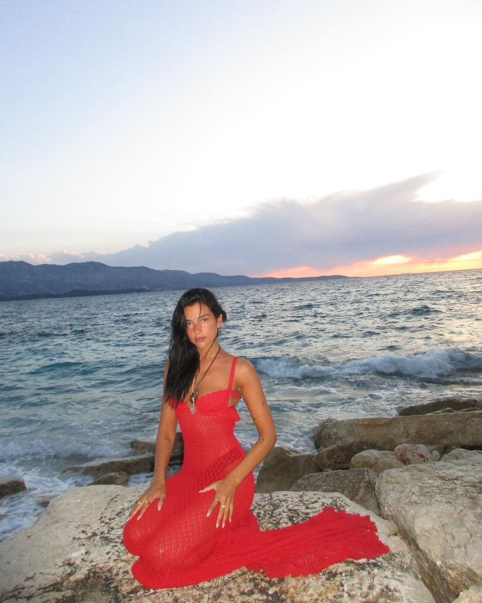 a person in a red dress on a rocky beach