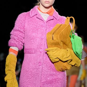 a person wearing a pink coat and holding a yellow purse