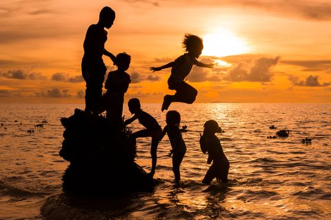 Kinderen spelen bij ondergaande zon op Arborek een eiland niet ver van een van de beste plekken op aarde om mantas te zien
