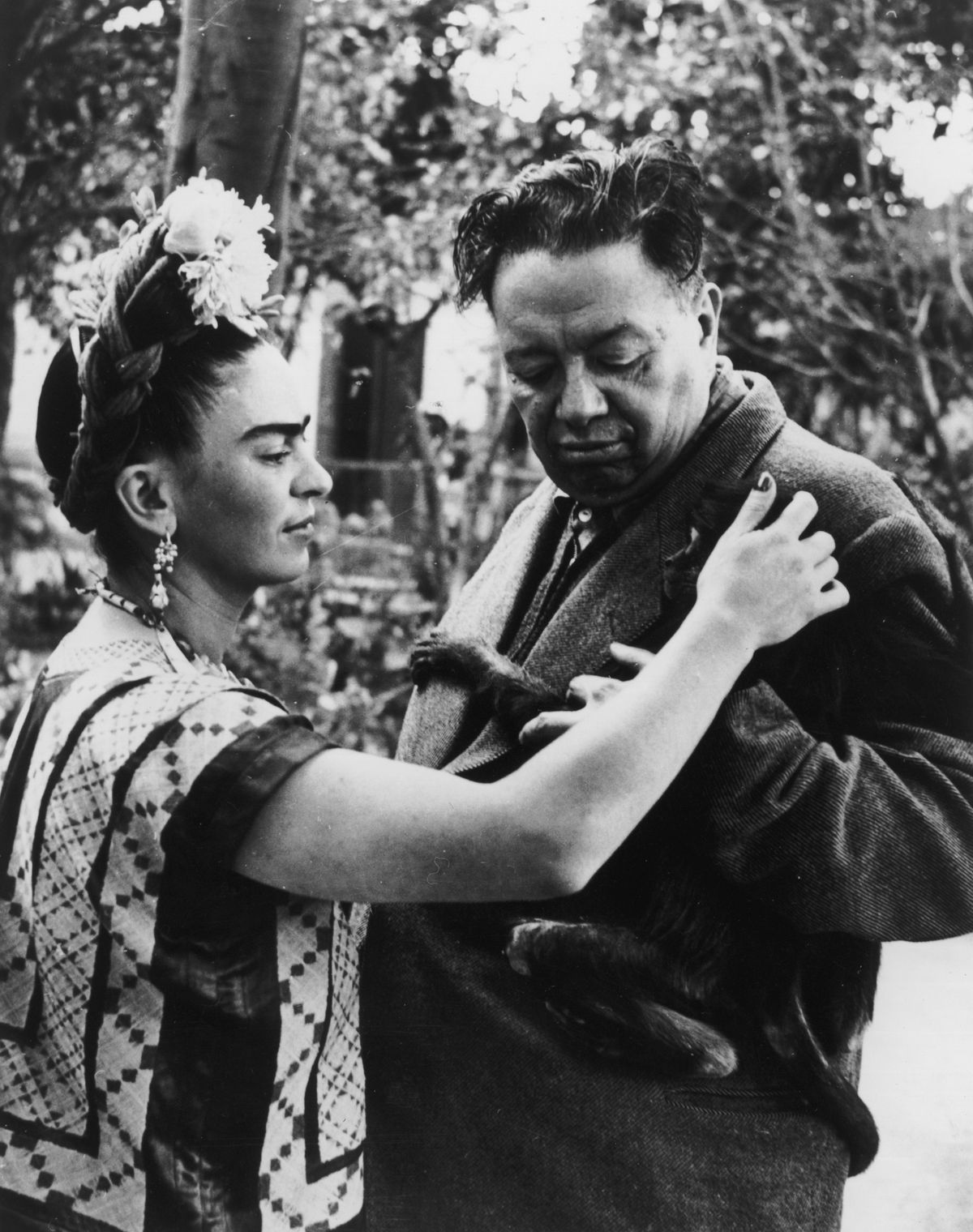 Frida Kahlo pets a monkey, possibly Fulang-Chang, clinging to the jacket of her husband, Mexican artist Diego Rivera