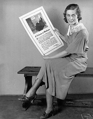 Een vrouw houdt een poster uit 1934 vast waarop reclame wordt gemaakt voor een moederdagpostzegel die door president Franklin Delano Roosevelt is ontworpen