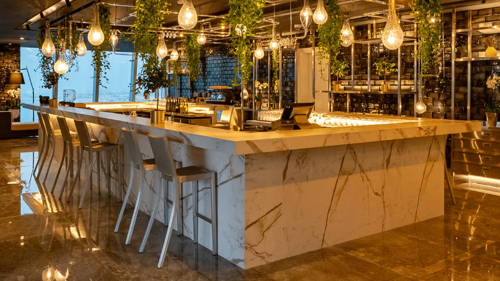 a modern bar area with a marble counter bar stools and pendant lighting