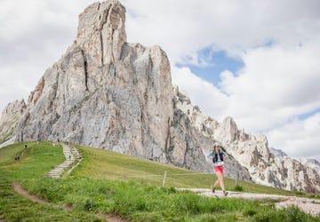 a person walking on a trail in front of a mountain