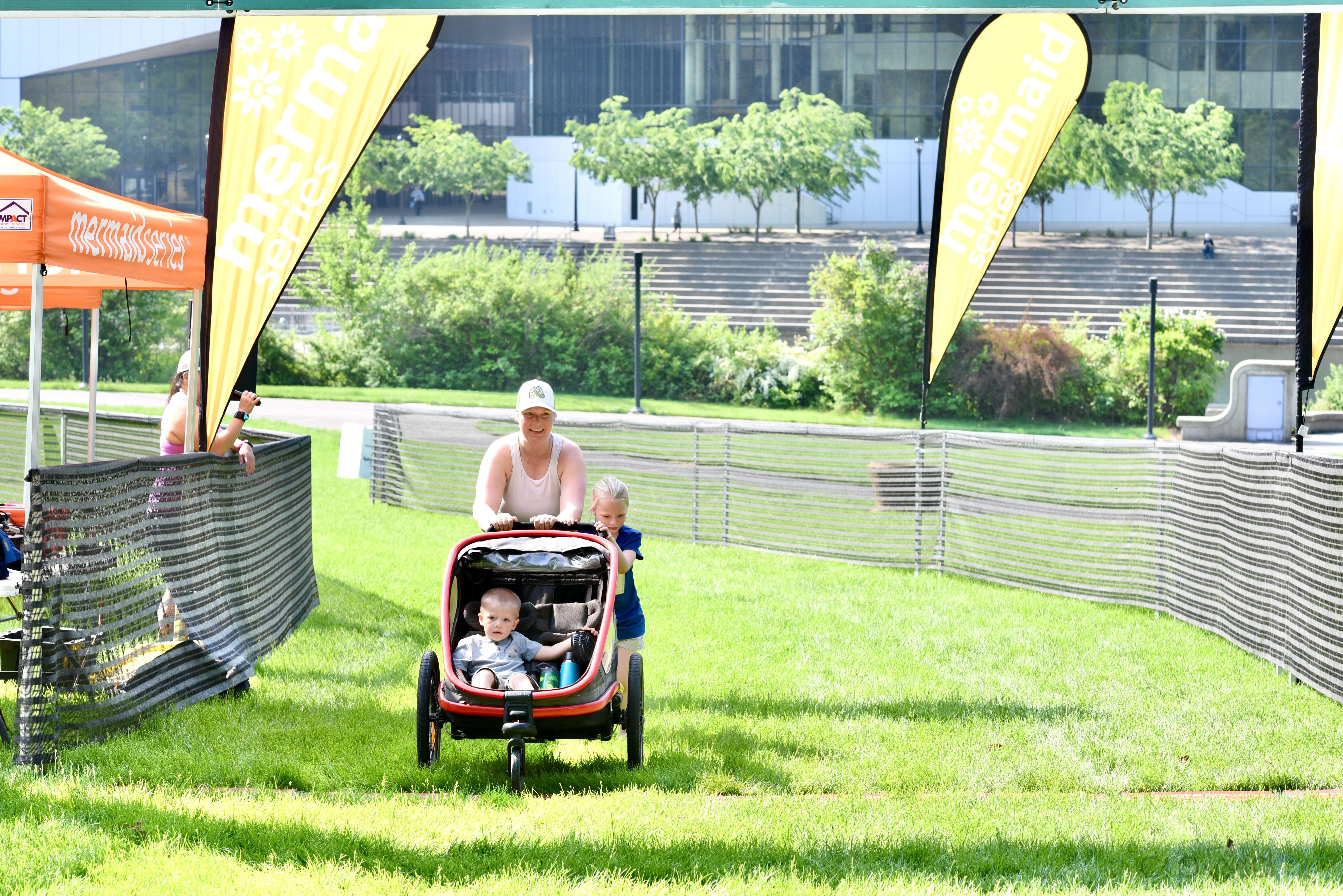 a person pushing a stroller with two children in a park event setting mermaid run spokane washington