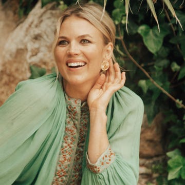 a woman sitting gracefully in a natural setting dressed in an embroidered green attire a woman sitting gracefully in a natural setting dressed in an embroidered green attire