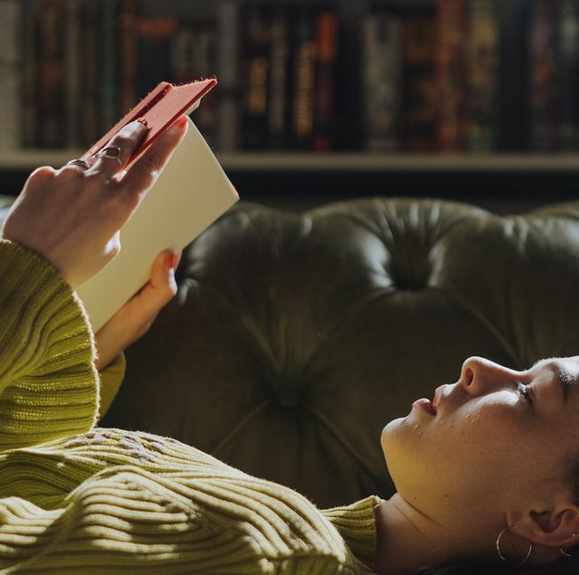 a person lying on a couch reading a book
