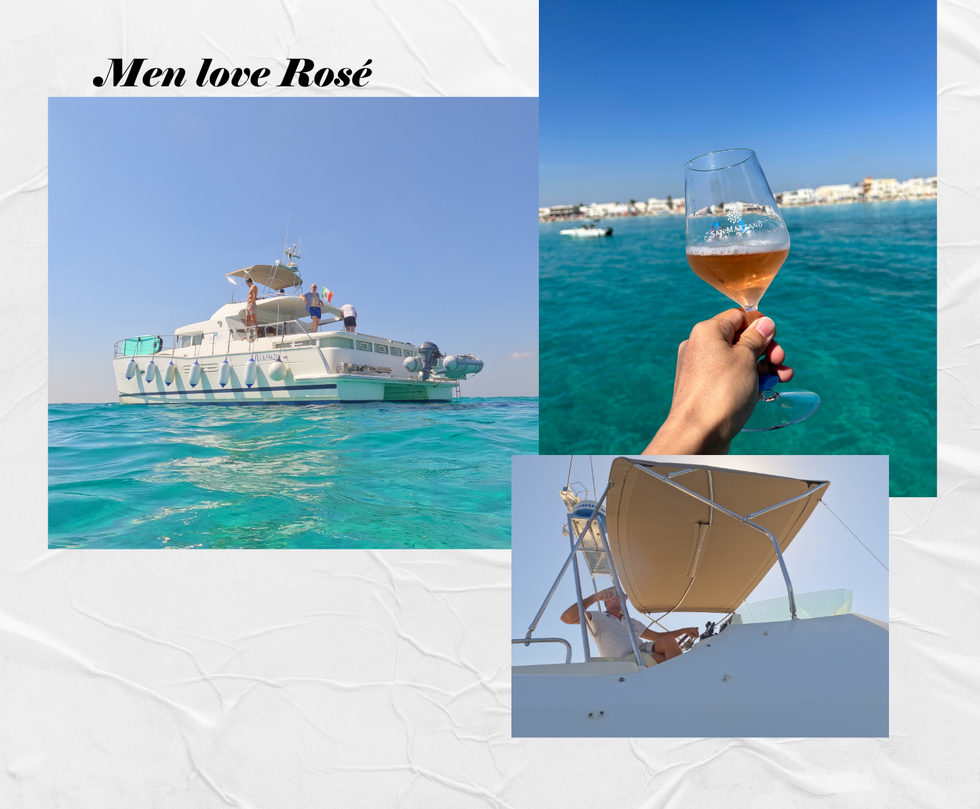 a hand holding a glass of wine in front of a boat