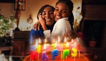 mom and daughter hugging in front of a birthday cake with colorful candles