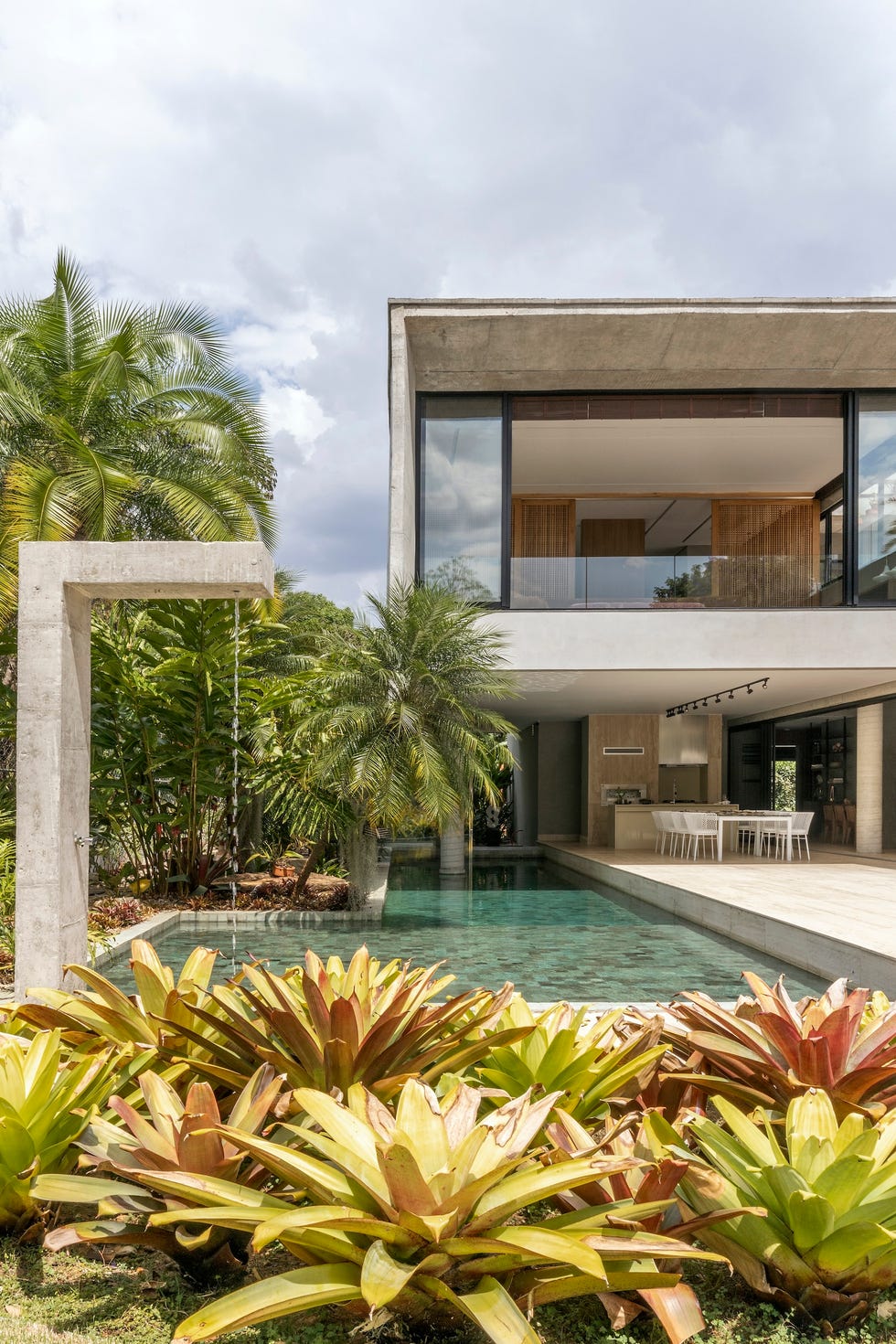 casa de hormigon con piscina que combina estructura brutalista, ventilacion cruzada y diseno tropical a medida