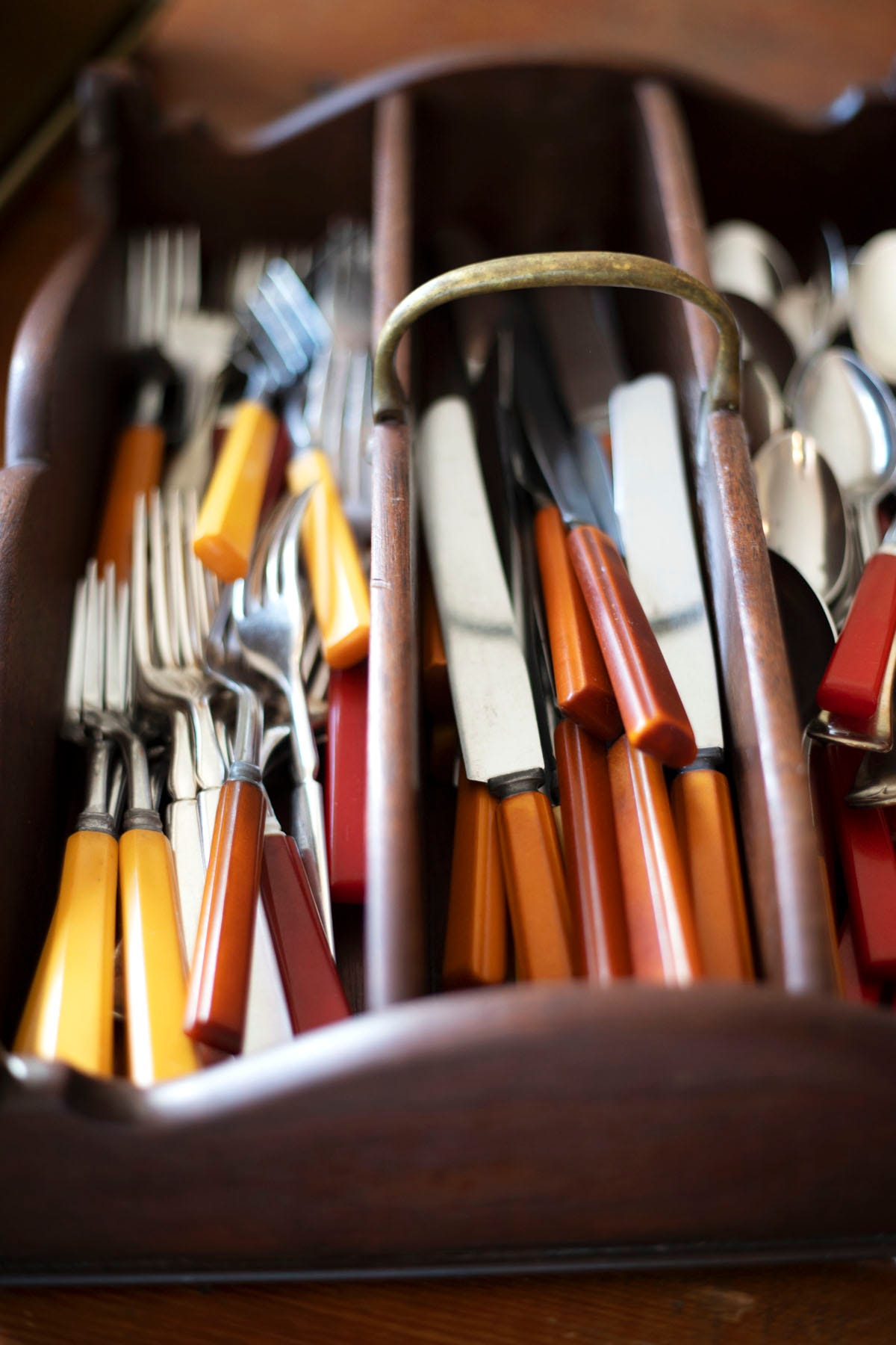 a silverware caddy filled with antique bakelite knives forks and spoons